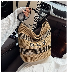 Dettaglio borsa tote in paglia con ricamo RLY nero e strisce negli interni di un'auto
