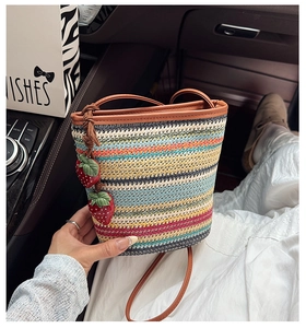 Détail d'un sac seau en paille tissée colorée avec charms fraises dans une voiture