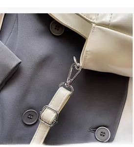 Detail of premium silver metal hardware and buckle on a cream leather tote handbag