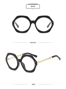 Detail of black hexagonal frame glasses with gold metal temples and silver rivet accents