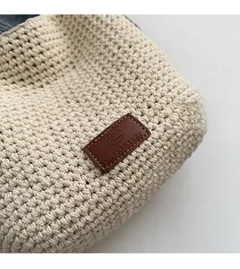 Close-up of beige cotton woven bag texture with premium brown leather logo patch detail