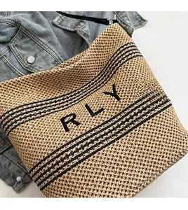 Dettaglio della borsa in paglia intrecciata con strisce nere e scritta RLY su denim