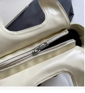 Detailed macro view of smooth silver metal zipper on cream white leather bucket bag