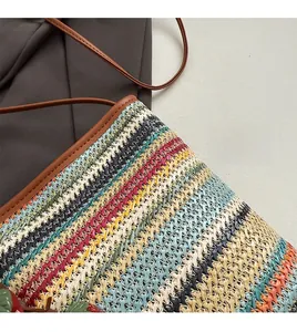 Détail d'un sac en paille tissé coloré avec motifs ondulés et bandoulière en cuir brun
