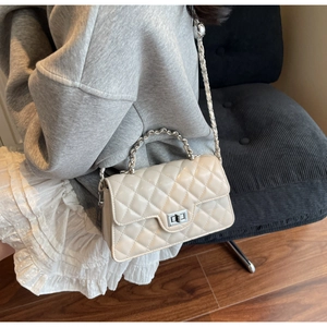 Chic beige quilted crossbody bag with silver chain strap shown in a lifestyle setting