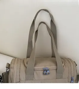 Detailed macro view of reinforced handles and dual metal zippers on a beige fitness bag