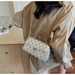 Close-up of a silver quilted leather baguette bag with a metal twist lock and chain strap