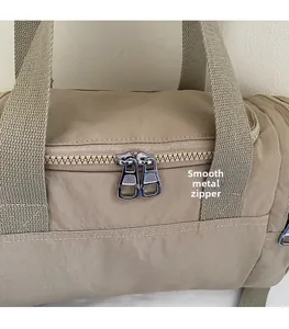 Detailed macro view of smooth dual silver zippers and durable woven nylon strap of the bag