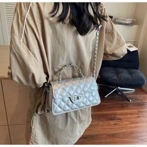 Silver quilted chain bag shown from a side view on a model wearing a trench coat