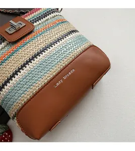 Detail of color-block woven straw bucket bag with brown leather flap and silver turn-lock