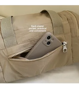 Close-up of the back zipper pocket on a khaki nylon travel bag showing a phone inside