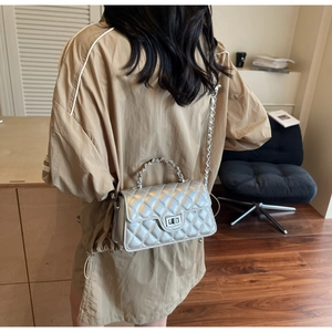 Detail shot of a silver quilted leather baguette bag with chain strap worn by a model