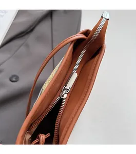 Détail d'une fermeture éclair argentée sur un sac à bandoulière en cuir marron
