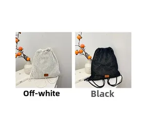 Detail of hand-woven knitted bucket backpacks in beige and black with leather logo patch