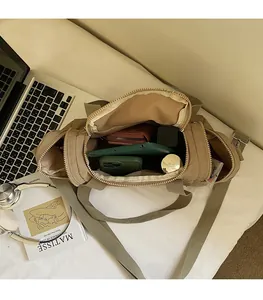 Macro view of khaki nylon crossbody bag showing large internal space and zipper compartments