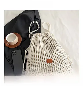 Detail of cream knit drawstring backpack with mesh texture and brown leather label