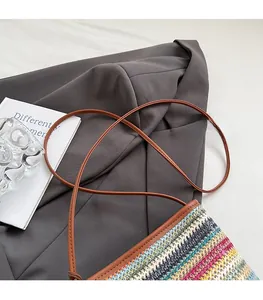 Détail d'un sac en paille tressé coloré avec bandoulière en cuir marron et coutures