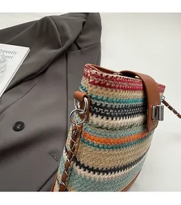 Detail of colorful striped straw bucket bag with leather buckle and chain strap