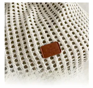 Detail of white knit hollow-out fabric with a decorative brown leather logo patch