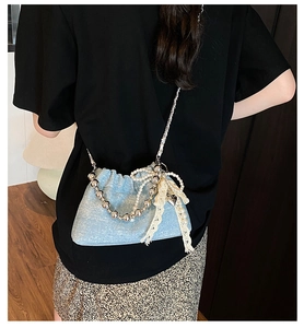 Close-up of light blue sequined bucket bag with silver bead handle and lace bow detail