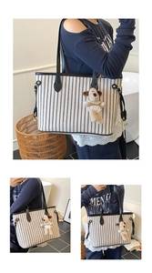 Detail of striped canvas tote bag featuring black leather handles and plush dog charm