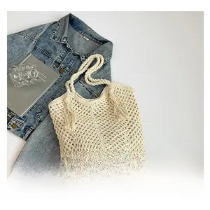 Detail of hand-woven crochet mesh texture and tassel accents on cream shoulder bucket bag