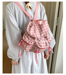 Détail du sac à dos à carreaux roses avec cordons et nœuds sur les poches avant