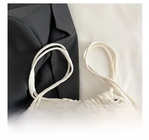 Detail of white crochet drawstring bag showing hollow knit texture and dual shoulder straps