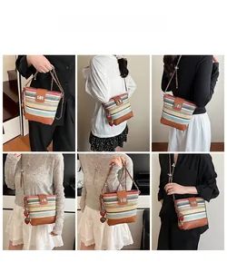 Detail of colorful striped straw bucket bag with leather base and strawberry charms