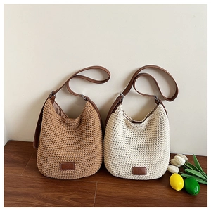 Detail of woven cotton shoulder bags with leather straps and logo patch on wood