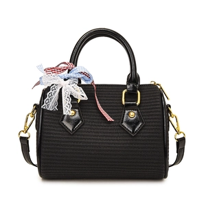 Sac cylindrique tressé noir avec nœud élégant et détails métalliques dorés