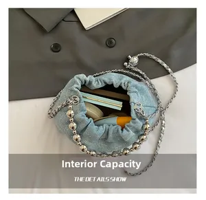 Internal capacity of sequined denim bucket bag showing cosmetics and silver chain