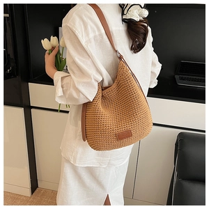 Detailed close-up of brown woven bucket bag featuring premium leather strap and logo patch