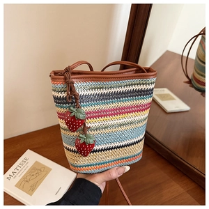 Détail du sac seau tissé coloré avec breloques fraises 3D et bandoulière en cuir