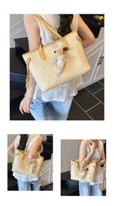 Detailed shot of yellow striped canvas tote with leather handles and dog plush pendant