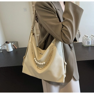 Detail of cream tote bag with gold chain, pearl strap and adjustable wide strap