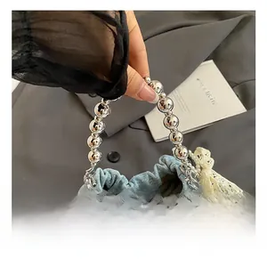 Close-up of denim bucket bag with silver metal bead handle and lace bow detail