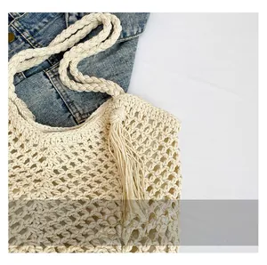 Close-up of beige crochet bucket bag featuring woven strap and long tassel fringe detail