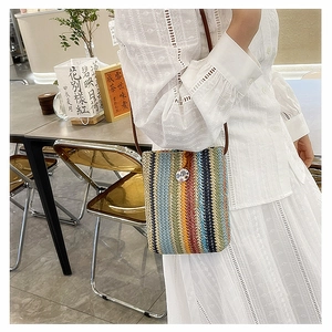 Close-up of rainbow woven mini crossbody bag with petal button and leather strap