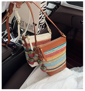 Close-up of woven straw crossbody bags with colorful stripes and strawberry charms