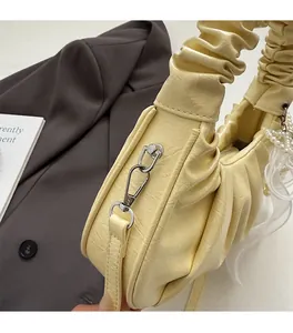 Détail du sac plissé jaune crème avec pendentif nœud en dentelle et perles
