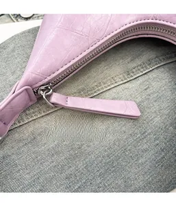 Detail of lavender crocodile embossed faux leather bag with silver metal zipper closure