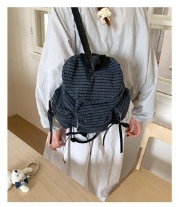 Vue détaillée d'un sac à dos à carreaux anthracite avec zips à ruban dans un intérieur