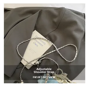Detail of adjustable silver chain strap with star-embossed metal ball lock on a bucket bag