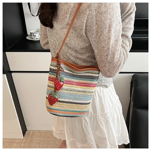 Detail der Regenbogen-Stroh-Beuteltasche mit zwei niedlichen roten Erdbeer-Anhängern