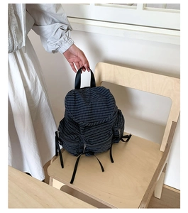 Détail du sac à dos à carreaux bleus avec cordons et poches latérales zippées spacieuses