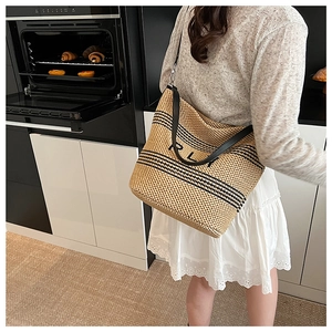 Dettaglio della borsa tote in rafia con strisce nere e logo RL sulla tracolla