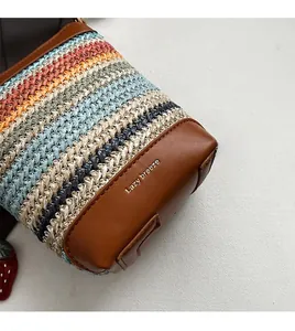 Detail of multi-color woven straw bag featuring brown leather base and embossed logo