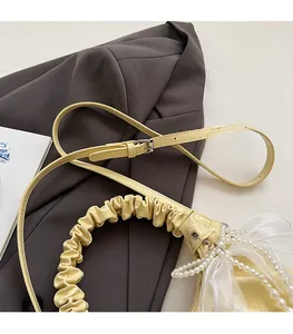Détail du sac nuage jaune avec chaîne en perles, nœud en organza et poignée plissée
