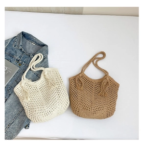Detail of woven straw tote bags in beige and tan with fringe tassels on white fabric